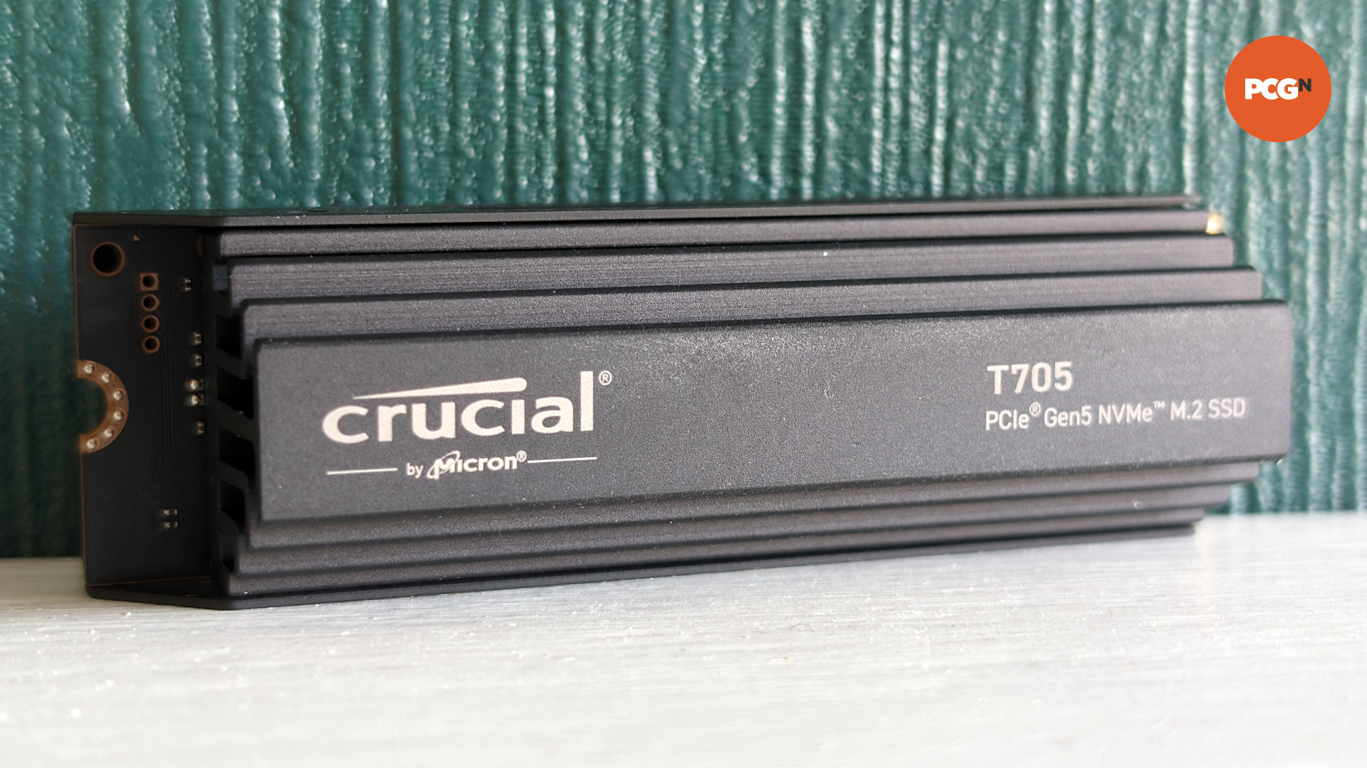 SSD Crucial T705 posé sur une surface blanche sur fond vert