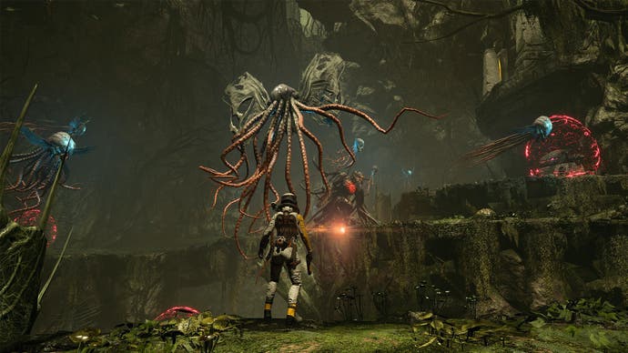 Capture d'écran de Returnal, montrant la protagoniste Selene debout devant une forme de vie extraterrestre ressemblant à une pieuvre.
