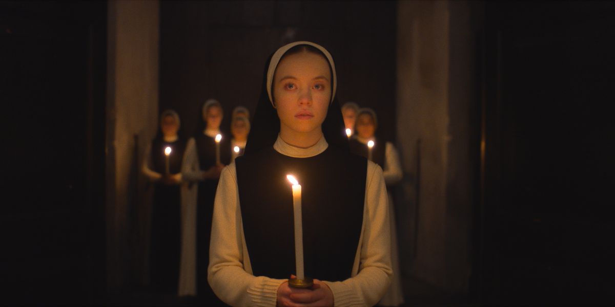 Sydney Sweeney dans Immaculate tenant une bougie avec des religieuses derrière elle 