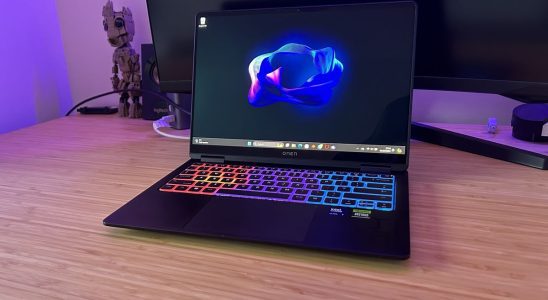 HP Omen Transcend 14 gaming laptop sitting on a wooden desk with a monitor behind