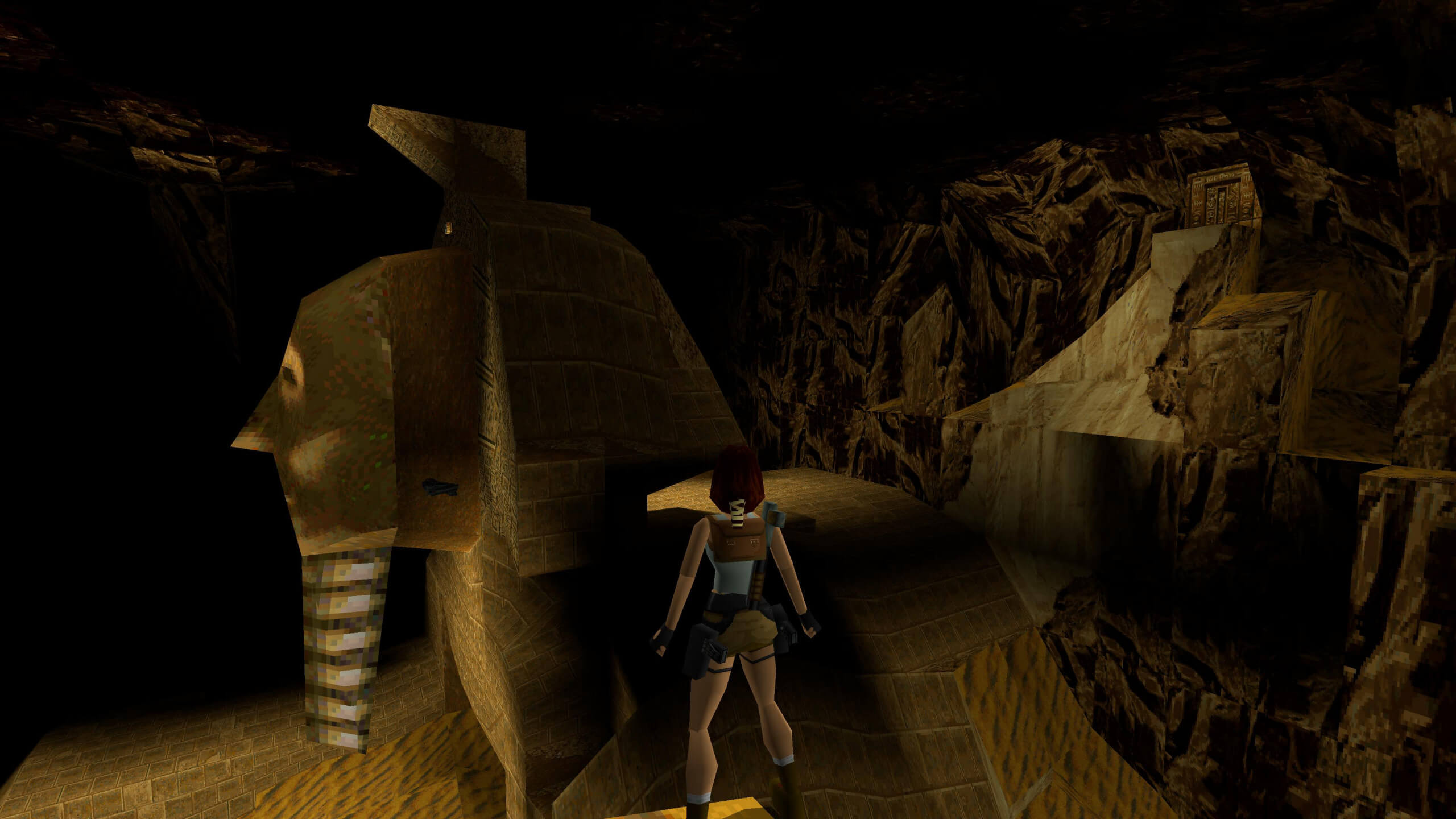 Lara se tient sur un rebord au milieu d'une ruine égyptienne.  Flottant dans les airs devant elle se trouve une paire d'Uzis, l'un des derniers secrets de ce chapitre.