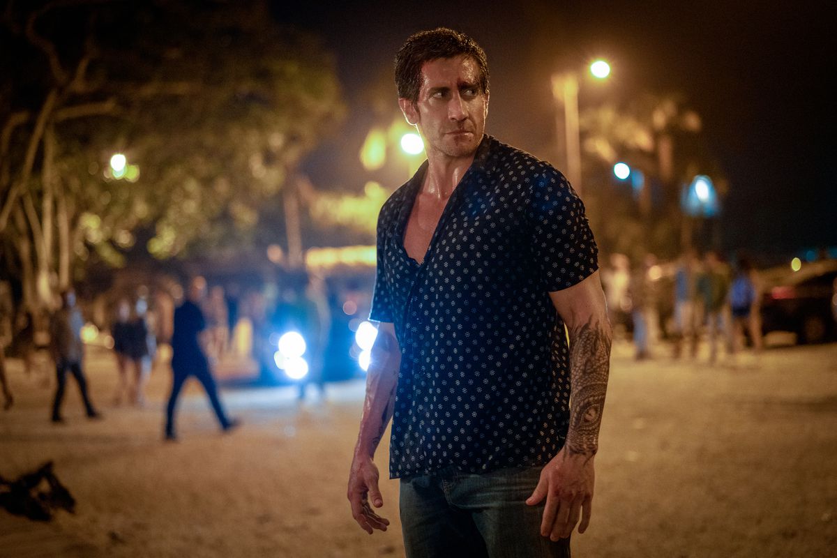 Un homme vêtu d’une chemise boutonnée debout dans une rue la nuit.