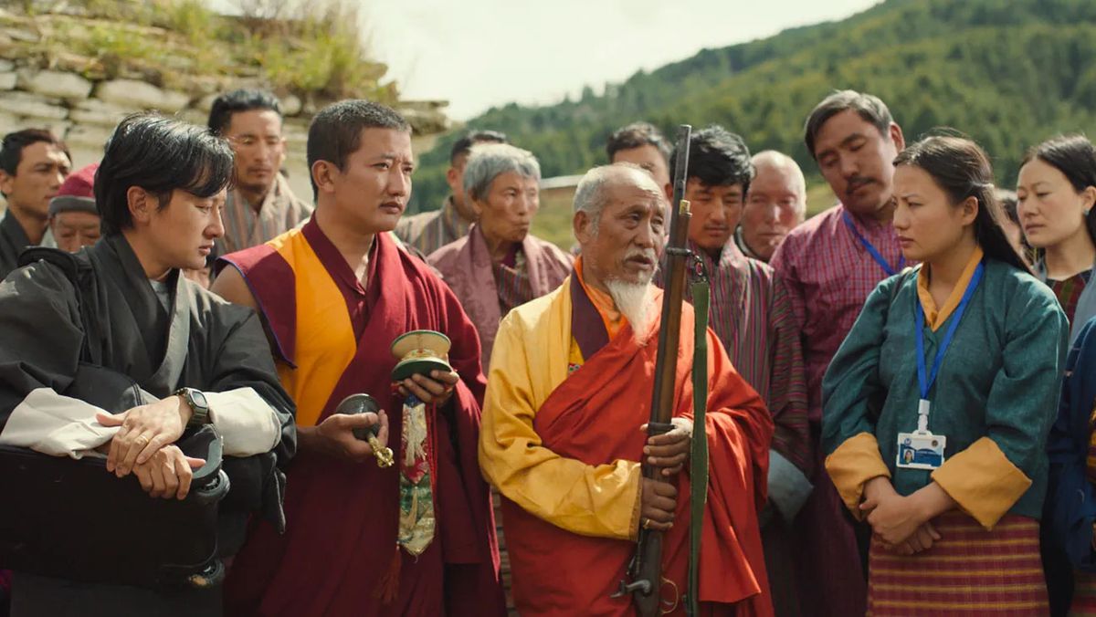 Un groupe de villageois et de moines admirant un fusil antique.
