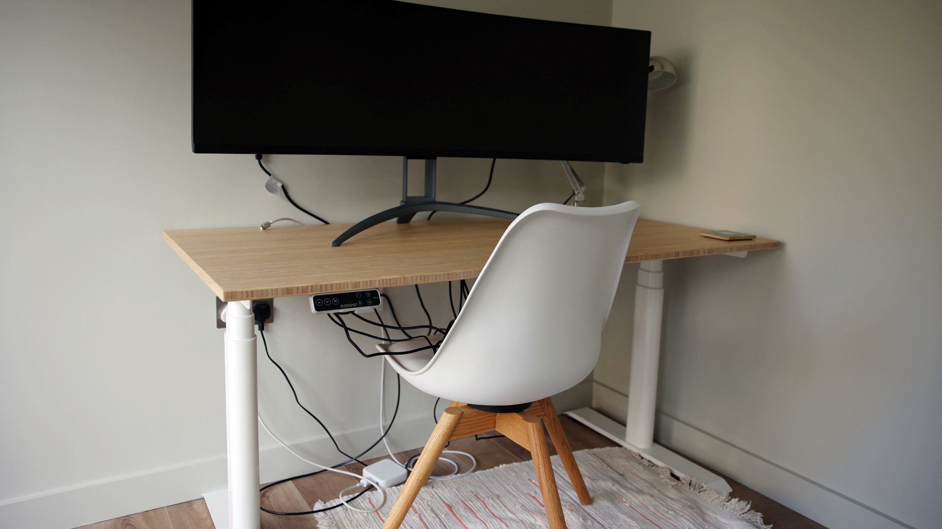 Image d'examen du bureau debout Flexispot E8 montrant le bureau sous un angle diagonal avec un moniteur dessus et une chaise installée.