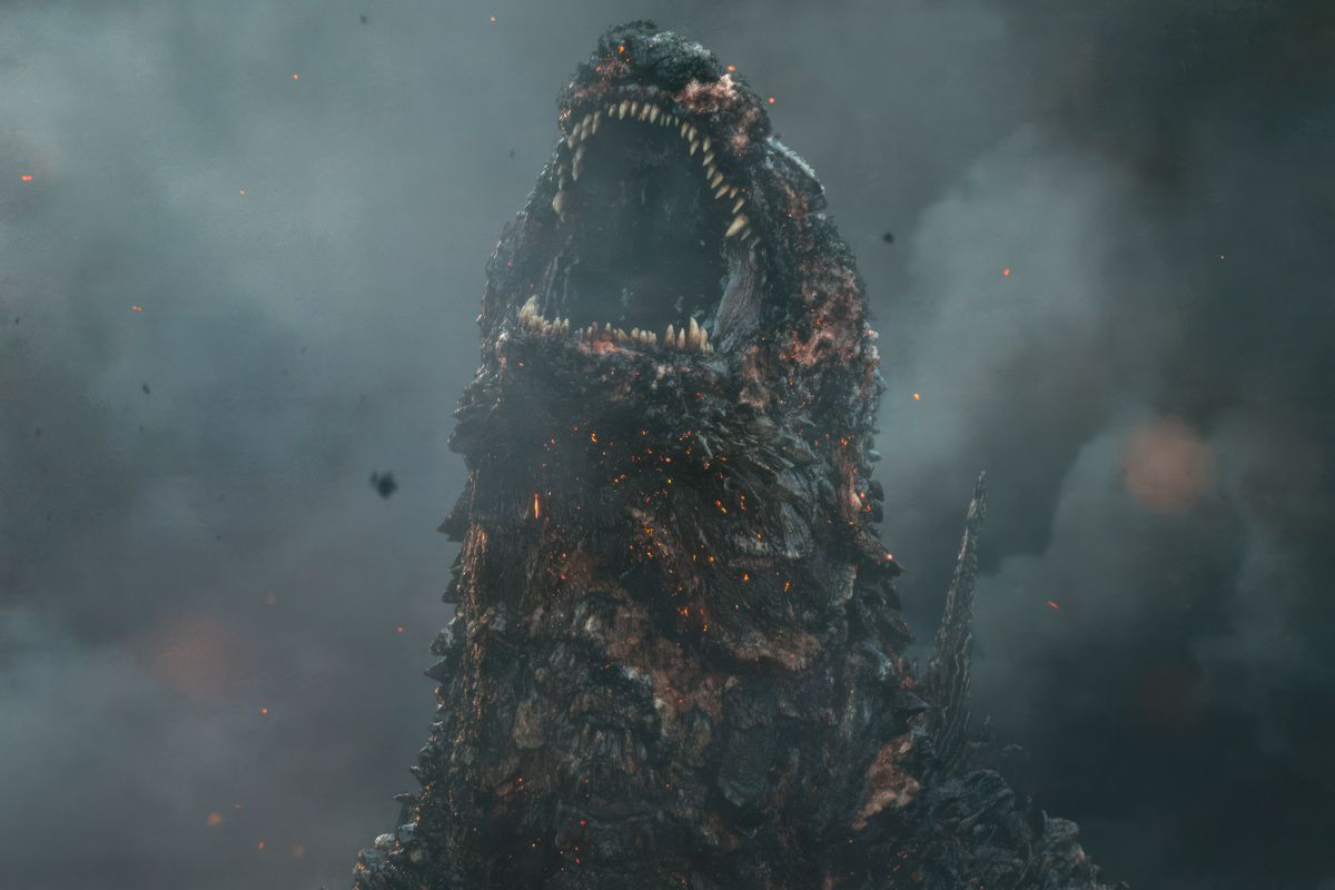 Un Godzilla à l'air brûlé avec une peau brune crépitante montrant des morceaux crus et brillants en dessous jette la tête en arrière et rugit dans Godzilla Minus One.