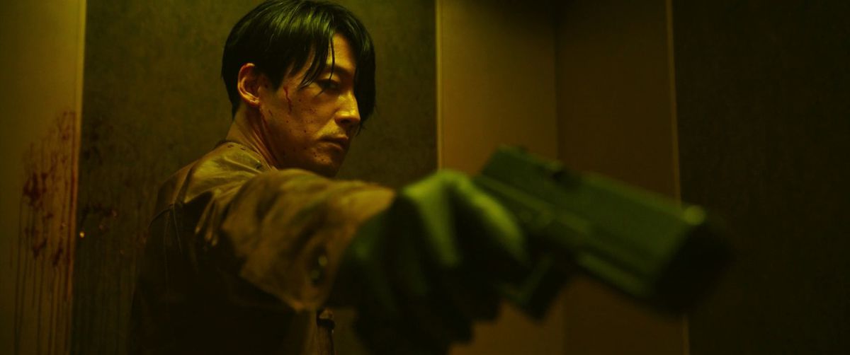 Dans The Killer : A Girl Who Deserves to Die, Jang Hyuk tient un pistolet légèrement incliné, avec du sang tout autour de lui.