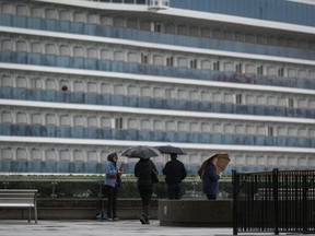 Les gens utilisent des parapluies pour se protéger de la pluie alors que le navire de croisière Princess Cruises Majestic Princess est amarré au port de Vancouver, en Colombie-Britannique, le lundi 25 septembre 2023.