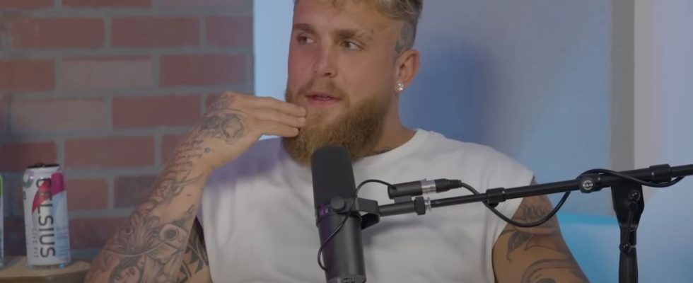 Jake Paul wearing a white shirt and touching his face