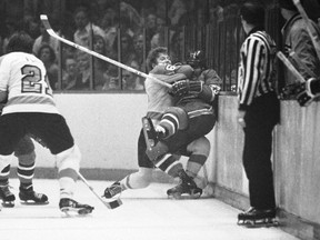 Le centre des Flyers de Philadelphie Bobby Clarke (16 ans) pousse le défenseur des Canadiens de Montréal Bob Murdoch (23 ans) sur les planches lors de la troisième période d'un match éliminatoire demi-finale de la LNH, le 22 avril 1973 à Philadelphie.  La famille de Murdoch affirme que le double champion de la Coupe Stanley souffrait d'encéphalopathie traumatique chronique, une maladie évolutive et mortelle associée à des traumatismes crâniens répétés.