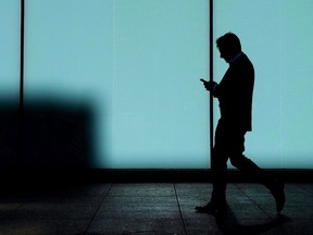Un homme marche et envoie des SMS sur son téléphone intelligent au centre-ville de Toronto, le 30 octobre 2017.