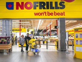 Un client pousse un caddie rempli de produits d'épicerie dans une épicerie NoFrills, à Toronto, le jeudi 23 novembre 2023.