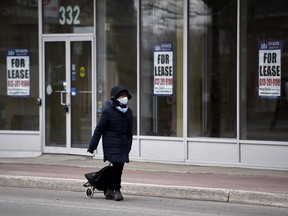 Une personne passe devant une devanture de magasin vide à Ottawa le 10 avril 2020.