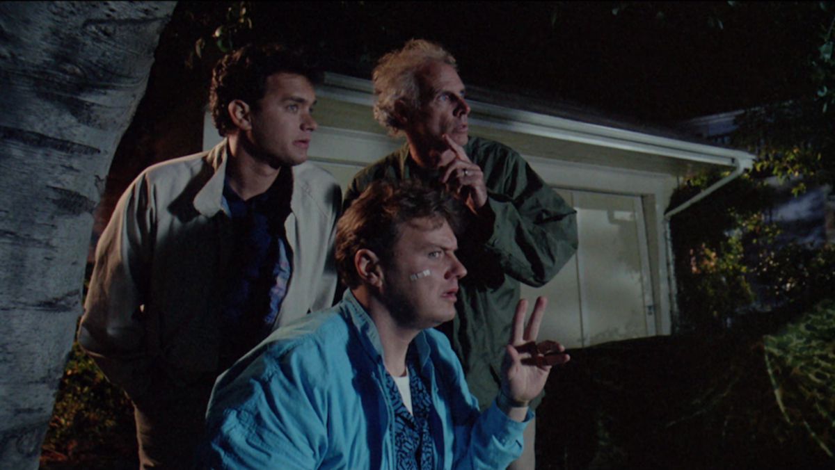 Trois hommes (LR Tom Hanks, Rick Ducommun, Bruce Dern) se cachent derrière une poubelle la nuit, regardant quelque chose hors écran.