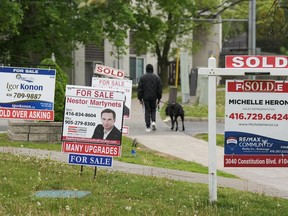 Les experts affirment que les fraudes liées aux titres de propriété et aux prêts hypothécaires connaissent une croissance rapide au Canada et que les propriétaires devraient prendre des mesures pour protéger leurs propriétés et leur identité.  Une personne passe devant plusieurs enseignes immobilières à vendre et vendues à Mississauga, en Ontario, le mercredi 24 mai 2023.