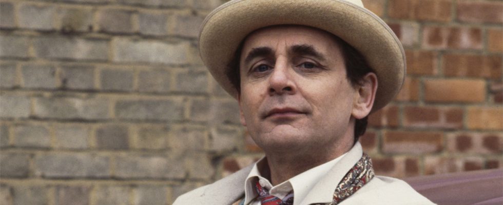 Sylvester McCoy in costume in a white suit and hat with an umbrella as the Seventh Doctor in Doctor Who