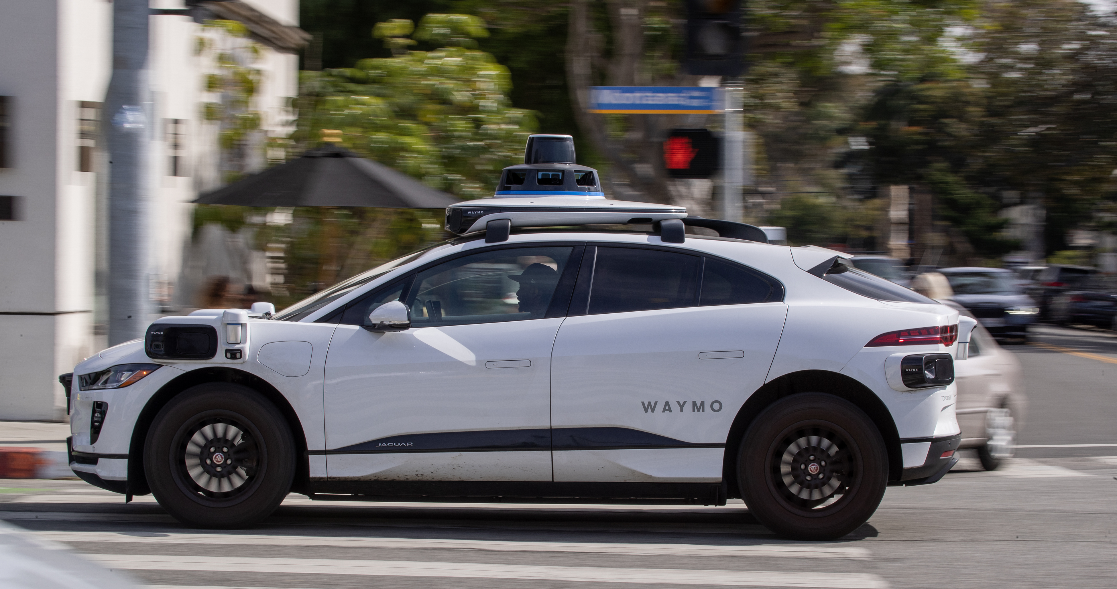 Un véhicule autonome Waymo circulant dans une rue bordée d’arbres à Santa Monica.